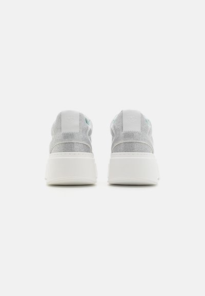Baskets gris clair avec une finition texturée, semelles blanches et un col rembourré. Présentent un design subtil avec des bords arrondis et un logo au niveau du talon.