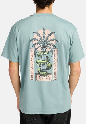 Lyseblå bomulds T-shirt med et stort grafisk motiv på ryggen, der viser et slange- og palmemotiv, akkompagneret af teksten "BALANCE OPPOSITES RVCA."