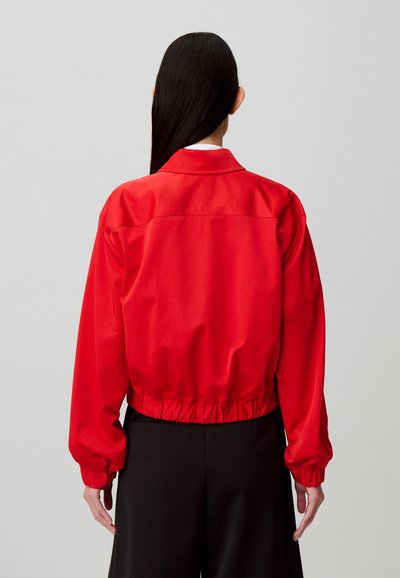 Giacca corta rossa in tessuto liscio, con collo a camicia e polsini e orlo elasticizzati. Design aderente.