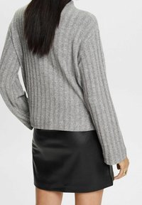 Harmaa ribbipaita pitkillä hihoilla, yhdistetty mustaan nahkahameeseen. Tekstuurit kontrastoivat, ja siinä on lyhyt malli sekä sileä pinta.