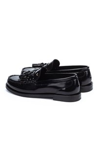 Par crnih sjajnih kožnih loafers s resicama i detaljima šivanja, fotografiranih na bijeloj pozadini.
