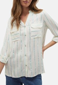 Chemise blanche à boutons avec des rayures verticales bleu clair, deux poches poitrine et des manches retroussables. Texture lisse et coupe décontractée.