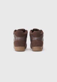 Braune High-Top Sneaker, die eine Mischung aus glatten und strukturierten Materialien, einen gepolsterten Kragen und eine strukturierte Gummisohle aufweisen.