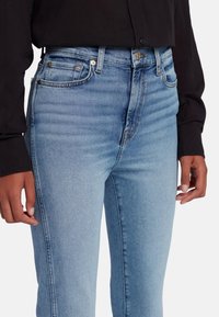 Jeans in denim azzurro chiaro con taglio dritto, design a cinque tasche e leggero sbiadimento. Dettagli in metallo e vita a media altezza.