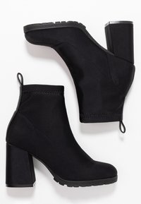 Bottines noires à talons hauts en tissu avec une surface lisse ; elles présentent un talon épais, un bout arrondi et une languette pour un enfilage facile.