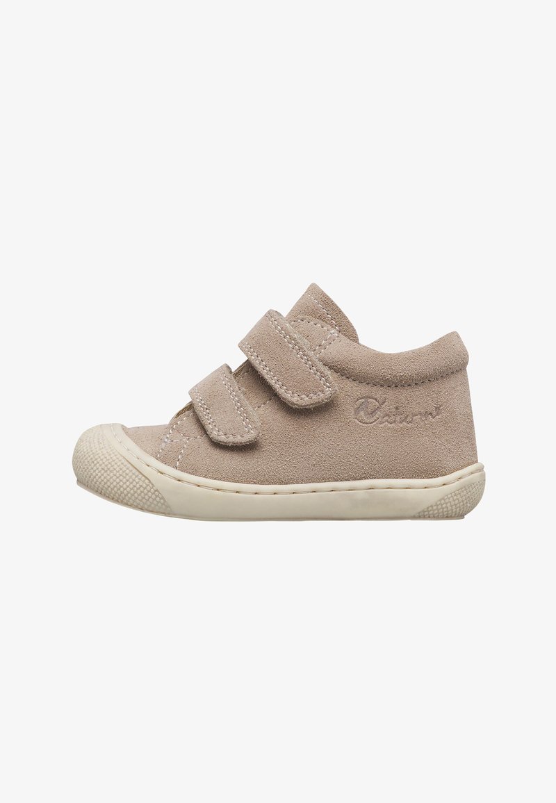 Chaussure pour tout-petit en daim beige avec deux bandes velcro, semelle en caoutchouc blanche et col rembourré, vue de côté sur fond blanc.