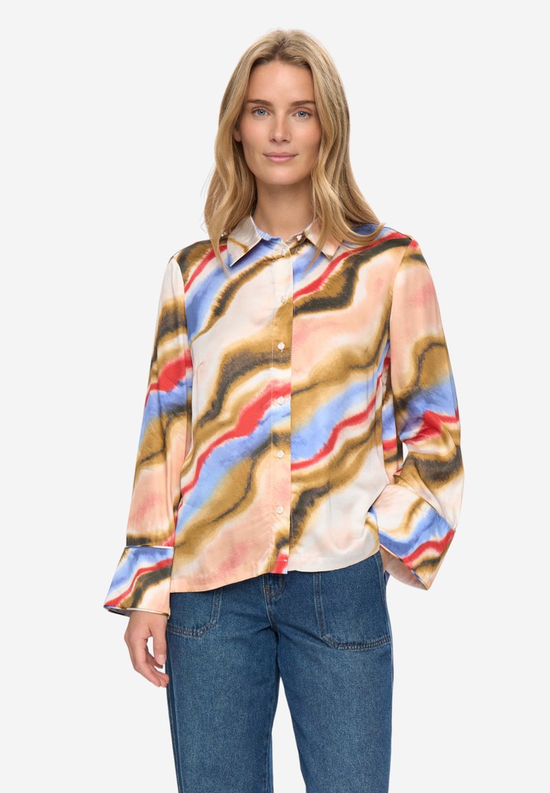 Blouse multicolore présentant un motif ondulé en nuances de crème, bleu, rouge et marron. Manches longues et col classique avec fermeture par boutons.
