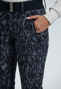 Sort og grå mønstrede bukser med en slim fit, der har en sidelomme med lynlås og en glat stoffinish. Inkluderer en kontrasterende linning.