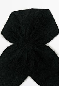 Bandeau tricoté noir fait de matériau doux et pelucheux. Il présente une forme de nœud avec une texture froncée au centre, créant une apparence lisse.
