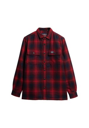 Camisa de franela a cuadros en rojo y azul marino con mangas largas, dos bolsillos frontales y cierres de botones. Textura suave y corte relajado.