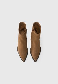 Bottines en suède marron avec un bout pointu et une semelle noire, dotées d'une fermeture éclair sur le côté pour un enfilage facile. Texture lisse avec un design ajusté.