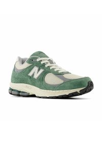Green and beige running shoe with a suede and mesh upper, rubber sole, and gray accents. Features laces and a cushioned collar.