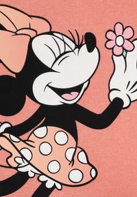 Minnie Mouse graphic on a pink background; she holds a pink flower and wears a polka-dotted skirt with a bow on her head.