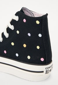 Černé vysoké tenisky Converse s bílými šněrovadly, vícebarevnými vyšívanými puntíky a bílou gumovou podrážkou s černým pruhem.