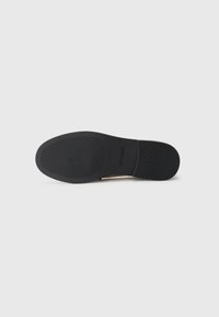 Sole of a black dress shoe with textured grip and "Steve Madden" logo embossed near the arch.