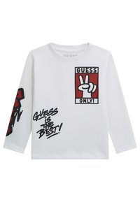 Tricou alb cu mâneci lungi, cu imprimeuri grafice în roșu și negru, având cutia "GUESS ONLY" și textul "GUESS is THE BEST!". Material moale.