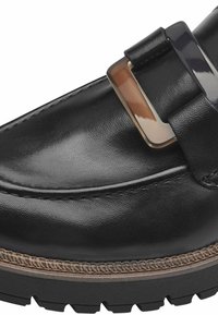 Mocassin en cuir noir avec une boucle rectangulaire argentée, des détails cousus le long du bord et une semelle en caoutchouc épaisse et texturée.