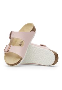 Sandalias de color rosa claro con un upper sintético texturizado, dos correas ajustables con hebillas de metal y una plantilla de corcho sobre una suela de goma blanca.