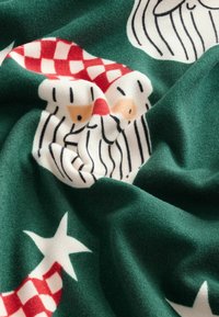 Zelená látka s potiskem tváří Santa Clause, červenými károvanými klobouky, bílými vousy a hvězdami, s měkkým, texturovaným vzhledem.