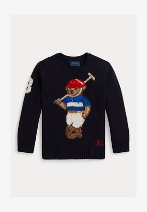 Marineblå genser med en strikket bjørn kledd som en polo-spiller som holder en kølle, iført rød hjelm, blåstripet skjorte, hvite bukser og støvler.