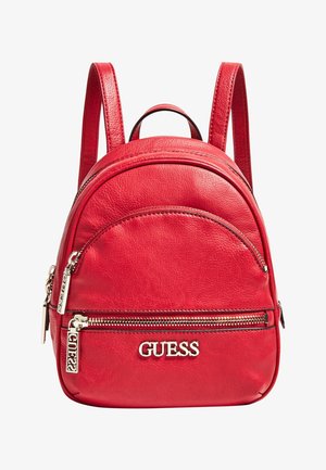 Petit sac à dos en cuir rouge avec deux compartiments zippés et logo GUESS argenté sur la poche avant.