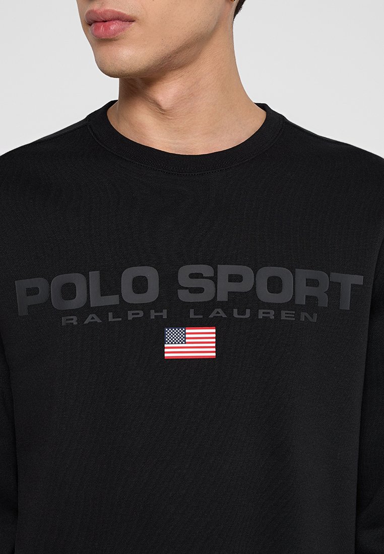 Felpa nera con la scritta "POLO SPORT" e "RALPH LAUREN" in grassetto grigio, con una piccola grafica della bandiera americana sottostante.