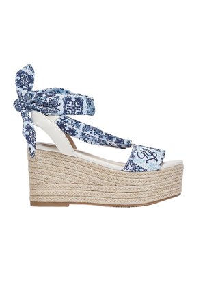 Sandalo con zeppa con piattaforma in juta intrecciata, suola bianca e cinturini in tessuto blu a fantasia legati intorno alla caviglia e al piede.