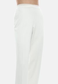 Pantaloni bianchi a gamba dritta con una vita elastica presentano una texture liscia. Il design è minimalista, senza pattern visibili o accessori.