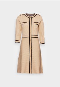 Beige quiltad klänning med svarta detaljer, gyllene knappar, trekvartslånga ärmar och två bröstfickor. A-linjeformad silhuett, knälång.