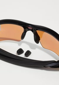 Óculos de sol desportivos com armação preta, lentes laranja e almofadas de nariz em borracha. Inclui dois pares adicionais de peças de ouvido em borracha preta.