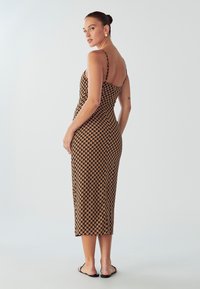Hnedé a čierne midi šaty s tenkými ramienkami, priliehavým strihom, geometrickým vzorom, hladkým materiálom a minimalistickým dizajnom.