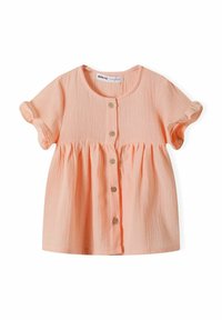 Chemisier à manches courtes en tissu doux pêche avec une finition texturée, présentant une taille froncée et quatre boutons en bois.