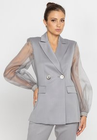 Szary dwurzędowy żakiet z przezroczystymi puff sleeves, dwiema przednimi kieszeniami i srebrnymi guzikami, charakteryzujący się dopasowanym krojem i gładką teksturą.