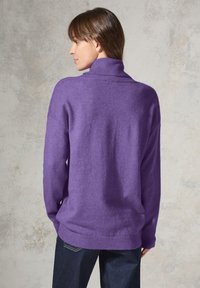 Overmaat pullover trui in levendig paarse brei. Heeft een hoge halslijn, geribde manchetten en zoom, met een ontspannen pasvorm en subtiele textuur.