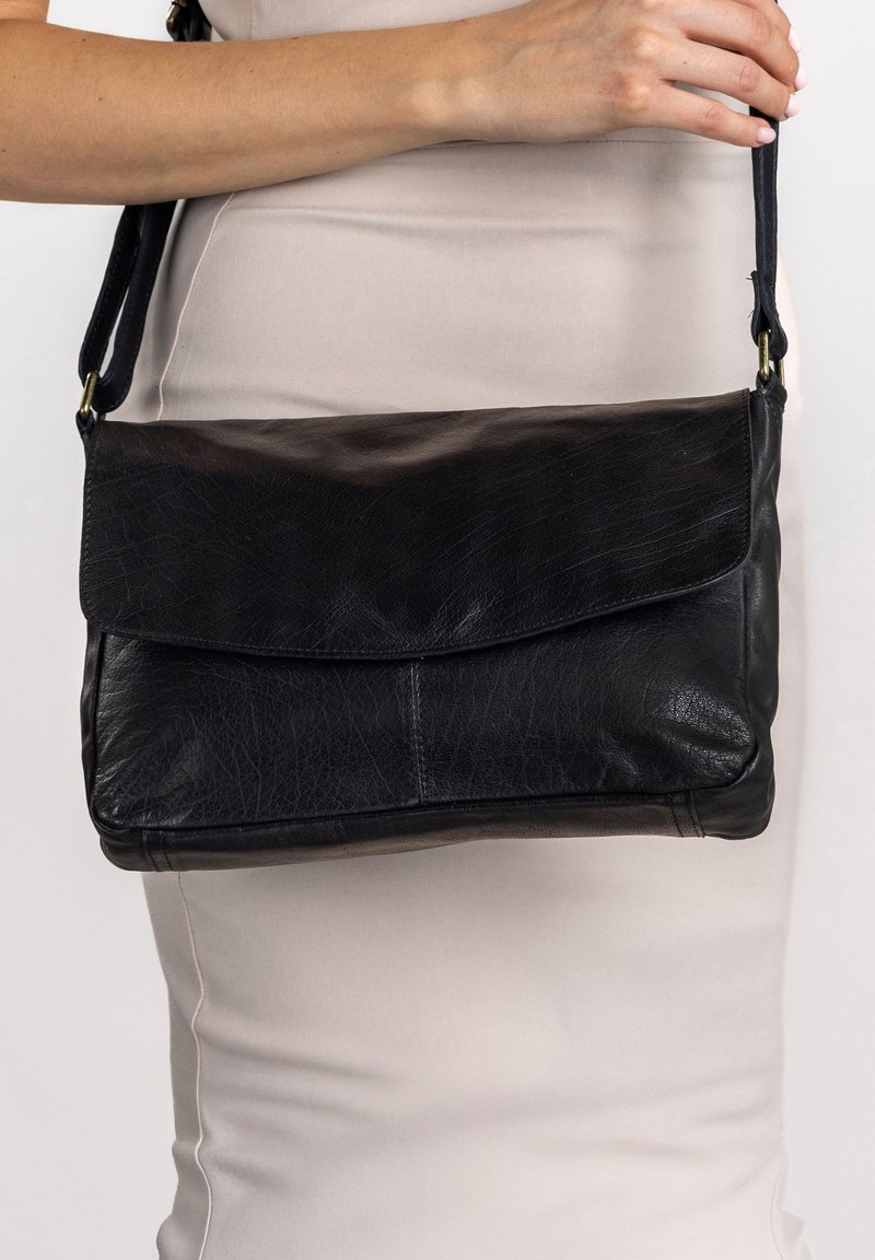 Svart läder crossbody-väska med en strukturerad design, vikbar klaff och en slät textur med minimala detaljer.