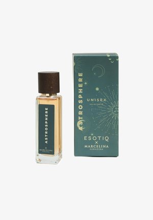 Przezroczysta szklana butelka na perfumy o prostokątnym kształcie, drewniana nakrętka i złota ciecz. Pudełko ma ciemnozielone tło z motywami niebieskimi.