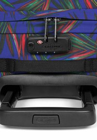 Valigia con tessuto blu vivace decorato con motivi a foglia multicolore. Dotata di accessori neri, lucchetto TSA e maniglia retraibile.
