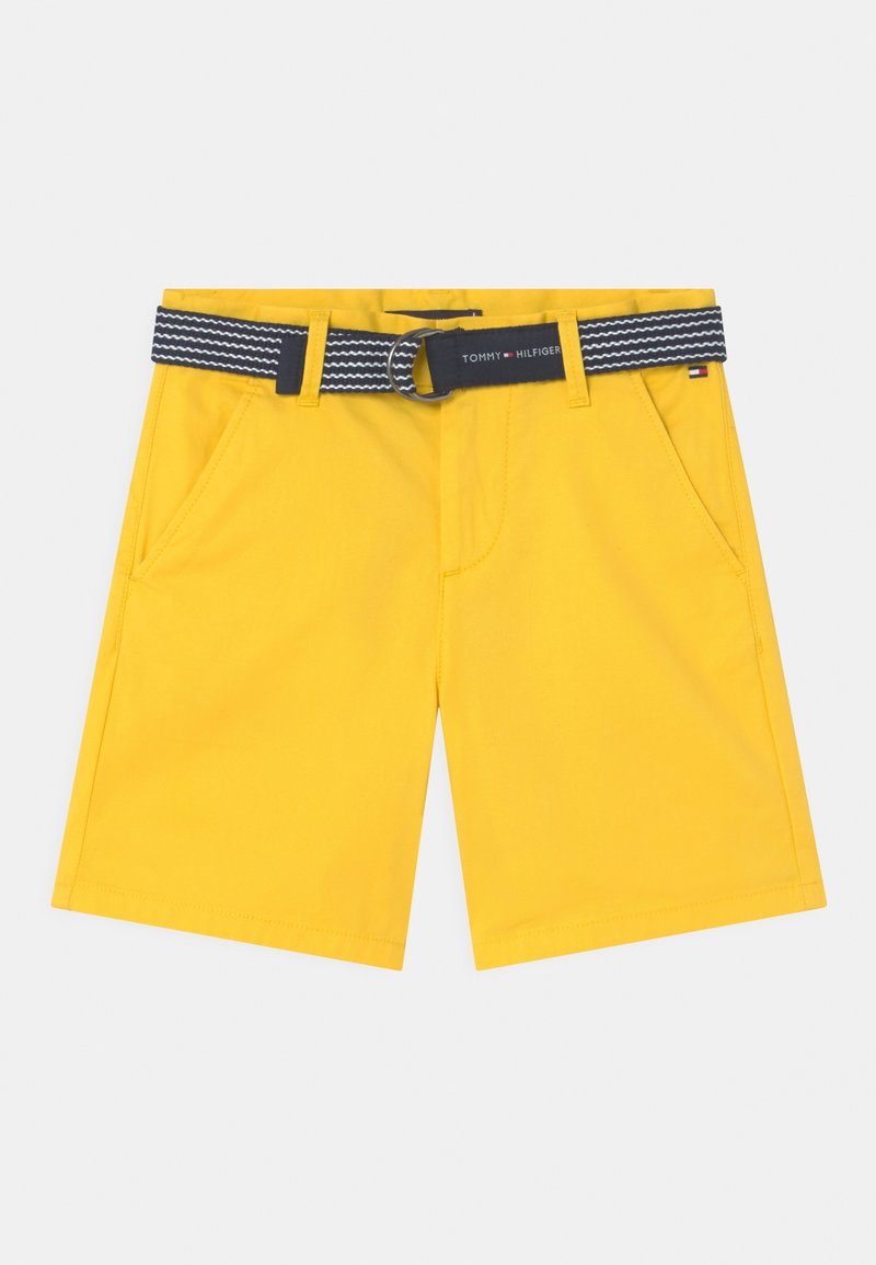 Shorts jaunes à la texture lisse, avec des poches latérales et une ceinture à motifs noir et blanc avec une boucle ronde.