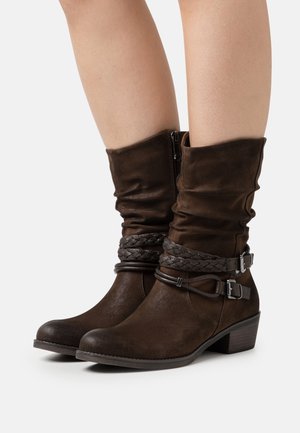 Braune Stiefeletten aus Kunstleder mit einem lässigen Schaft, geflochtenen Akzenten, seitlichem Reißverschluss und Blockabsatz. Strukturierter Stoff mit matter Oberfläche.