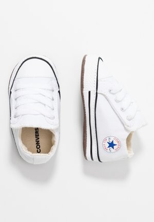 Paire de baskets Converse All Star blanches pour bébé avec bordure noire, lacets et logo étoile bleu sur le côté sur fond blanc.