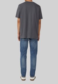 Szara bawełniana koszulka z krótkim rękawem, luźny krój i okrągły dekolt, zestawiona z jasnoniebieskimi dżinsami i casualowymi białymi butami.