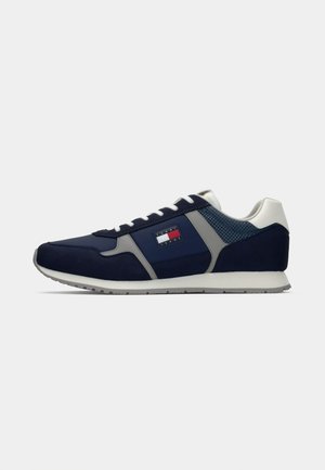 Mørkeblå treningssko med semsket og mesh-materialer, grå detaljer, hvite lisser og et logo-merke på siden. Klassisk joggesko-design.