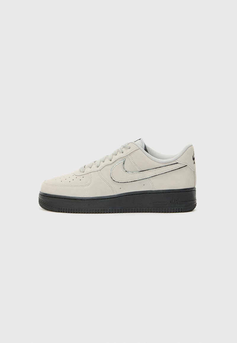 Suede gray sneaker with black rubber sole, round toe, perforated vamp, and white stitching. Features a silver Nike logo on the side.