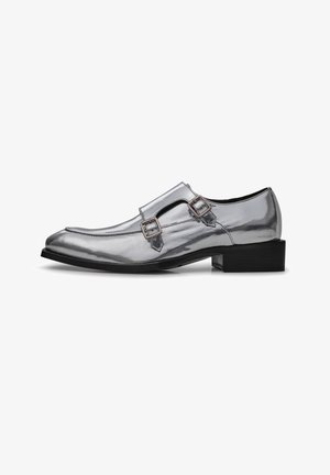 Silver patent leather shoes with a pointed toe and twin buckle accents. Features a low black heel and smooth, glossy surface texture.