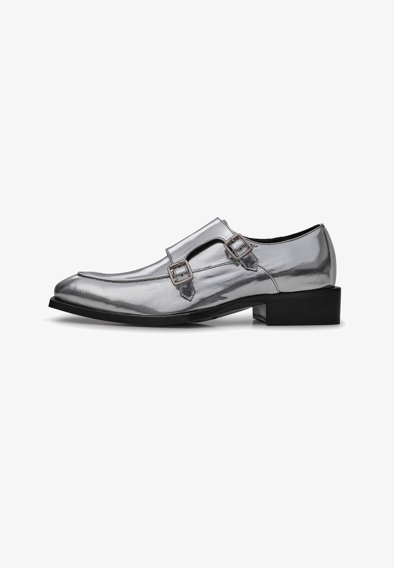 Silberne Lacklederschuhe mit spitz zulaufender Zehenpartie und doppeltem Schnallenakzent. Sie verfügen über einen niedrigen schwarzen Absatz und eine glatte, glänzende Oberflächenstruktur.