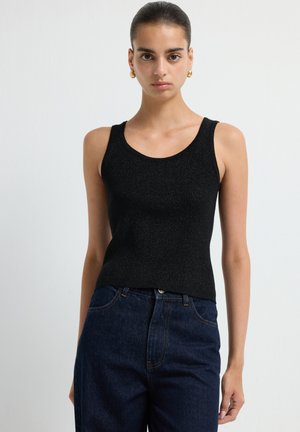 Zwarte geribbelde tanktop met brede banden, aansluitende pasvorm en gestructureerde stof, gecombineerd met hooggeprijsde donkerblauwe spijkerbroek.