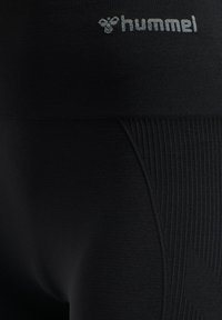 Zwarte geribbelde sportleggings met het witte "hummel"-logo nabij de tailleband.