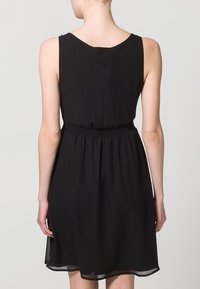 Robe noire sans manches présentant une coupe décontractée, une taille élastique, et une jupe fluide se terminant au-dessus du genou avec une texture lisse.