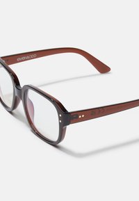  Schildpad vierkante bril met transparante glazen. Lichtbruine armen met een donkerder tint. Metalen accenten op het kader. Merk: even&ODD.