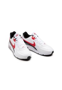 Zapatillas Nike Air Max con un upper de cuero blanco predominantemente, acentos rojos en el swoosh y el talón, forro negro y una suela acolchada.